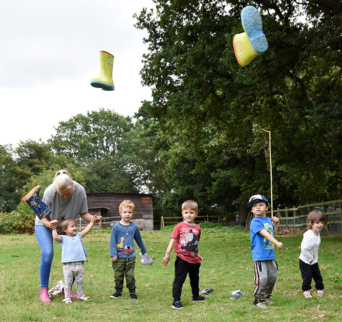 Preschool children throwing wellies in the nursery sports day event